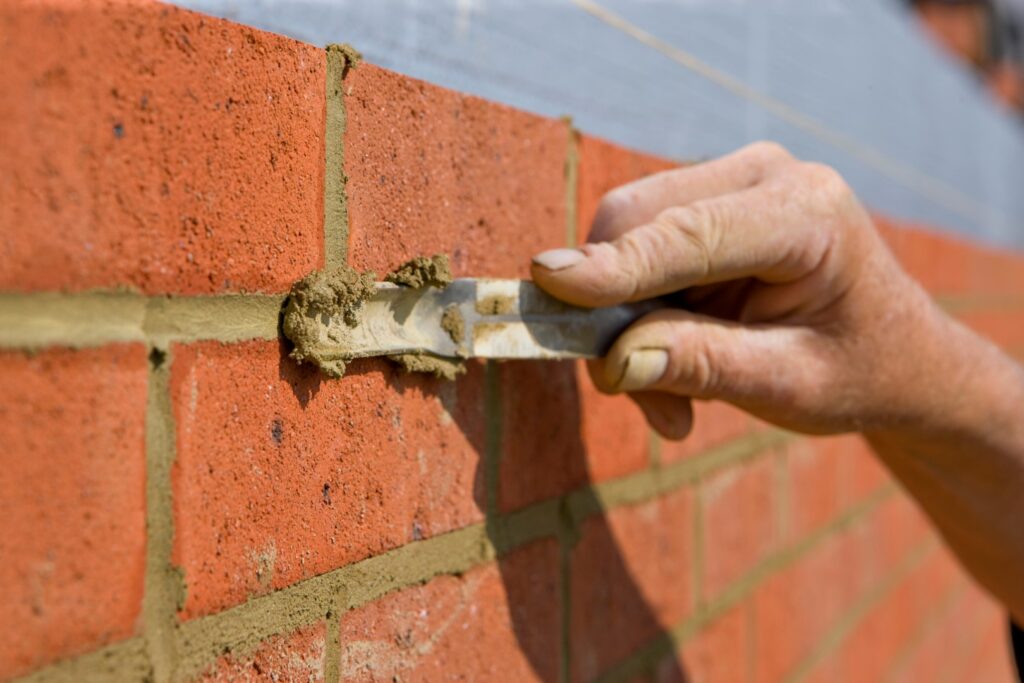 Jointer trowel repointing fresh mortar into a brick wall